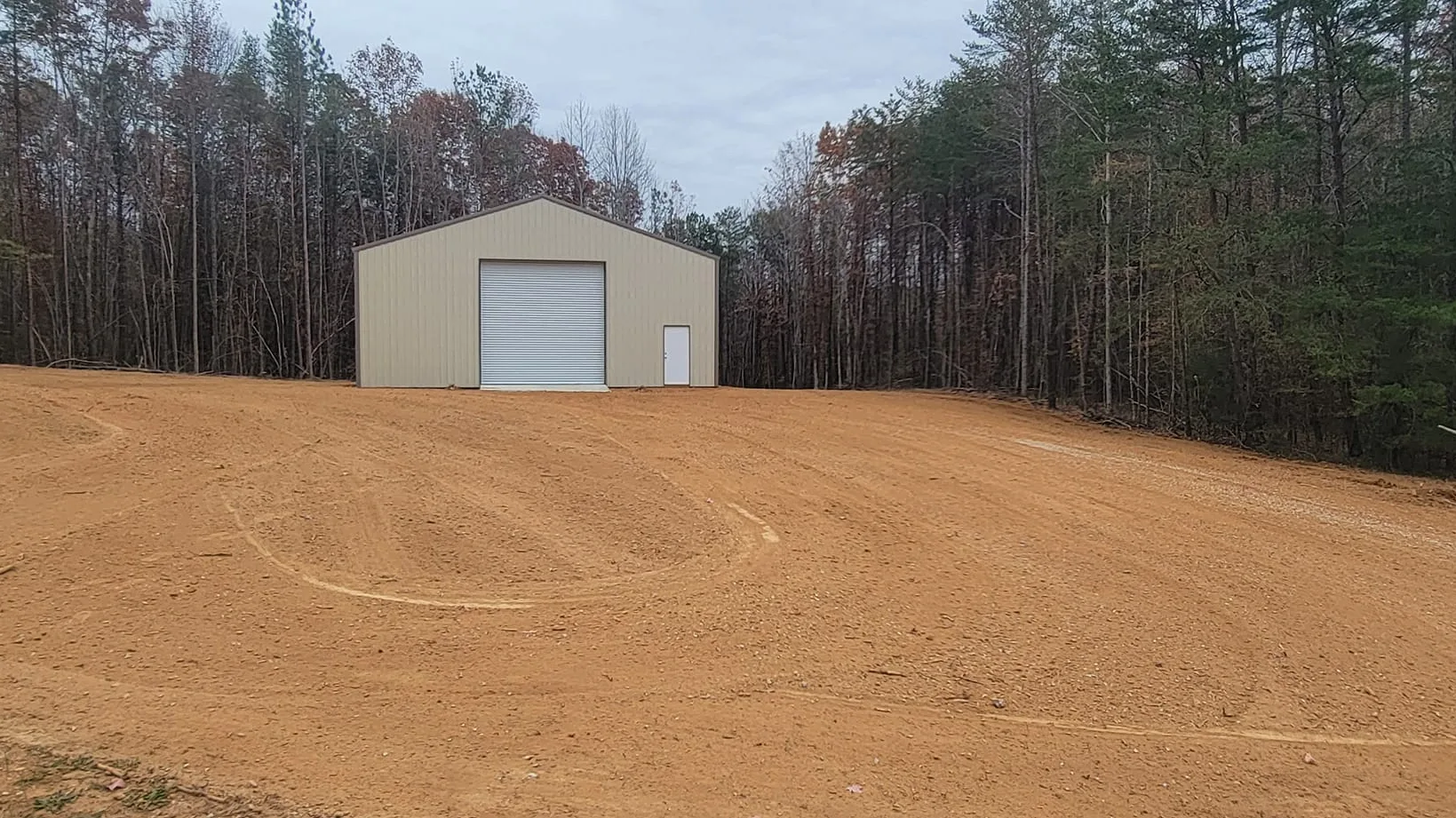 Pad graded and seeded beside a metal building