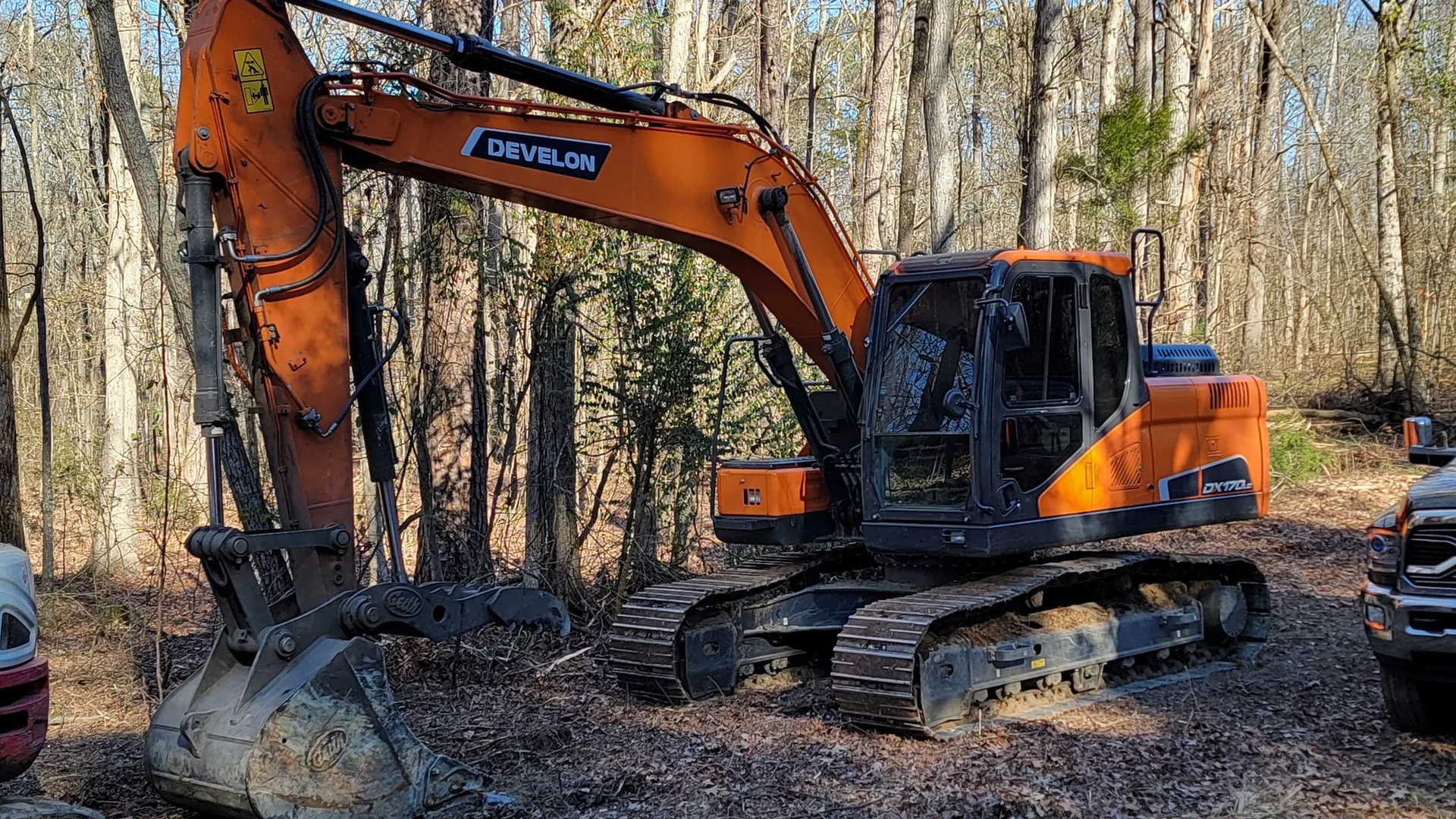 Land clearing crew pushing over southern pine trees with a tracked machine on red clay in Alabama